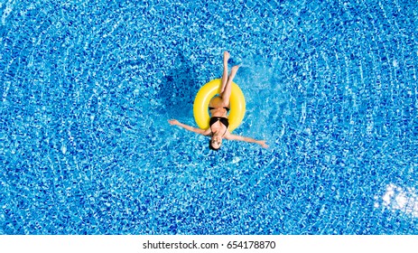 Attractive Woman In Swimsuit In The Yellow Rubber Ring In The Swimming Pool From Above