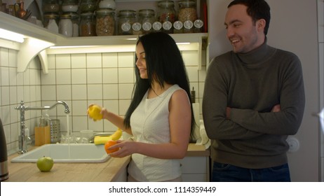 Attractive woman washing fruits and talking with handsome man in the kitchen - Powered by Shutterstock