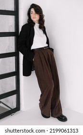 Attractive woman wear business look. Brunette model wear white shirt, black men's jacket and brown baggy pants. Winter, fall autumn or spring minimal outfit. - Shutterstock ID 2199061313