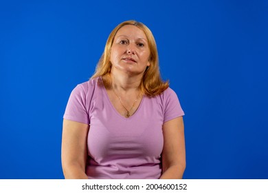 Attractive Woman Wearing Blank Purple Shirt On A Blue Background. Posing Concept