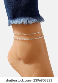 Attractive Woman wearing blue jeans showing anklet  on her ankle on white background