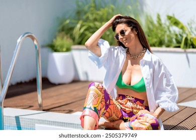 Attractive woman wearing white shirt and swimwear while relaxing by the poolside. Copy space.  - Powered by Shutterstock