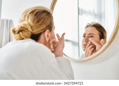 attractive woman in white comfy bathrobe wearing her contact lenses near mirror in bathroom - Powered by Shutterstock