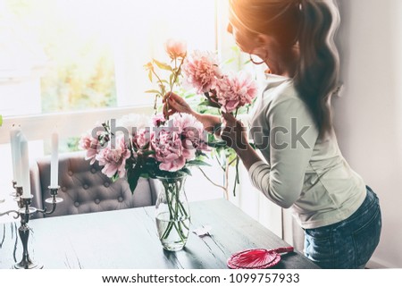 Similar – Woman with peonies on table in the living room