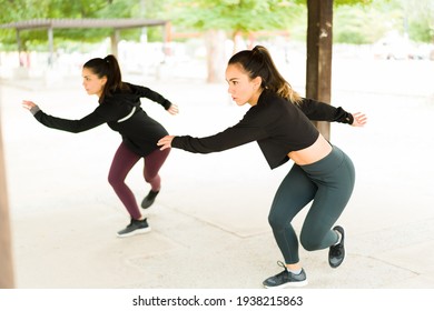 Attractive Women Doing Lateral Bounds During A Cardio Workout At The Park. Fit Latin Women Exercising With A HIIT Routine Outdoors