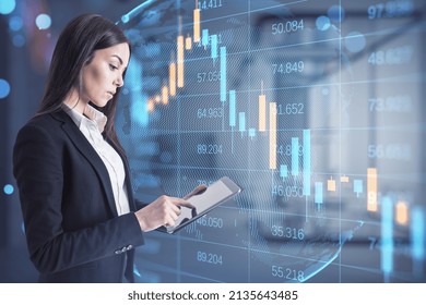 Attractive worried young businesswoman using tablet while standing in blurry office interior with abstract falling candlestick forex chart. Trade, economy and crisis concept. Double exposure - Powered by Shutterstock