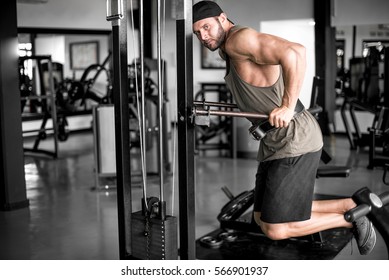 Attractive young adult man doing dips exercise in modern fitness center. Toned image.