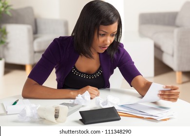 Attractive young African American woman working on finances at home wearing purple jacket sitting at dining table. - Powered by Shutterstock