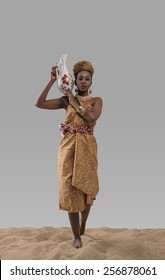 Attractive Young African Woman Carrying Jug With Water On Sand On Gray Studio Background