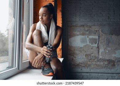 Attractive Young African Woman Holding Bottle With Water While Taking A Break In Gym