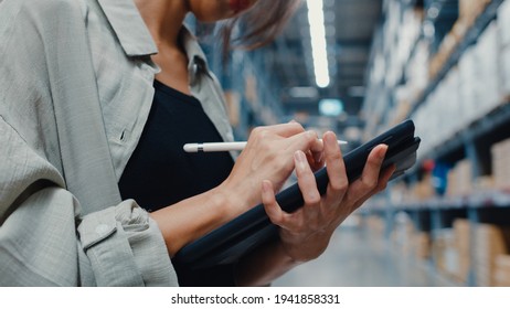 Attractive young Asia businesswoman manager looking for goods using digital tablet checking inventory levels standing in retail shopping center. Distribution, Logistics, Packages ready for shipment. - Powered by Shutterstock