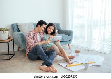 Attractive Young Asian Adult Couple Looking At House Plans.