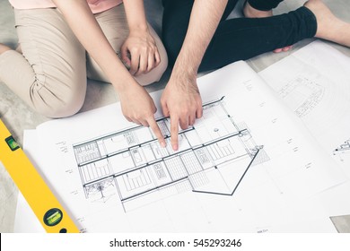 Attractive Young Asian Adult Couple Looking At House Plans.