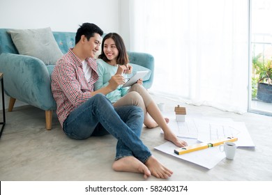 Attractive Young Asian Adult Couple Planning New Home Design.