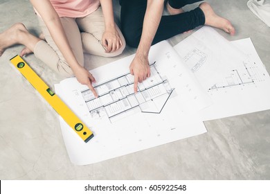 Attractive Young Asian Adult Couple Looking At House Plans.