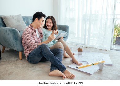 Attractive Young Asian Adult Couple Looking At House Plans.