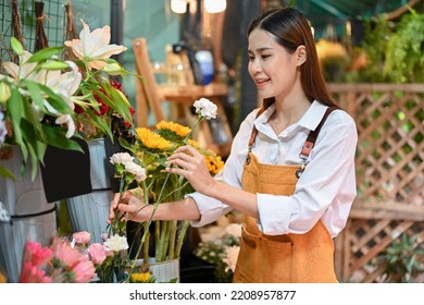 Attractive Young Asian Female Florist Or Flower Store Owner Arranging Flowers In A Vase In Her Shop. Small Business Owner Concept