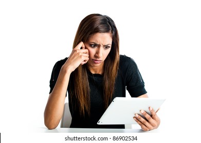 Attractive young asian indian teenage woman, working with a portable tablet computer looking angry and frustrated