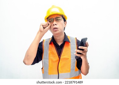 Attractive Young Asian Male Construction Worker Or Engineer In Orange Safety Vest And Yellow Hardhat Holding Phone With Sad, Crying, Dissapointed Expression