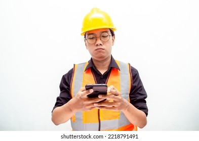 Attractive Young Asian Male Construction Worker Or Engineer In Orange Safety Vest And Yellow Hardhat Holding Phone With Sad, Crying, Dissapointed Expression