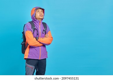 Attractive Young Asian Man Crossing Arm And Looking Sideways On Blue Background