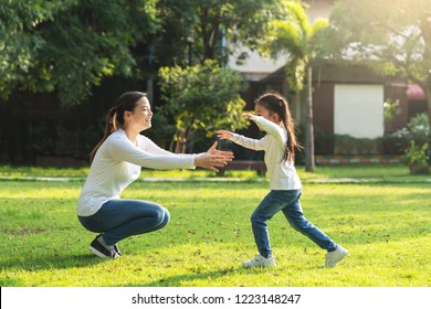 Attractive Young Asian Mother And Little Cute Girl Daughter Run To Hug Her Mom In Garden After Back School In Evening. Mom And Kids Feeling Relax Enjoy Playing Outside Concept. Bonding In Asia Family.