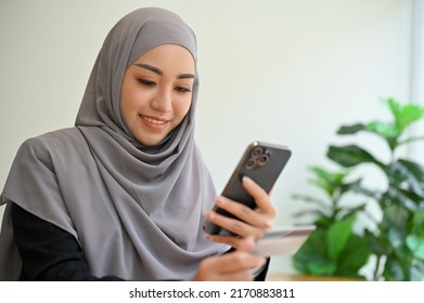 Attractive Young Asian Muslim Woman With Hijab Using A Smartphone, Chatting With Someone, Scrolling On Social Media, Searching Something On The Internet.