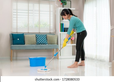 Attractive Young Asian Woman Mopping Tile Floor At Living Room While Doing Cleaning At Home During Staying At Home Using Free Time About Their Daily Housekeeping Routine.
