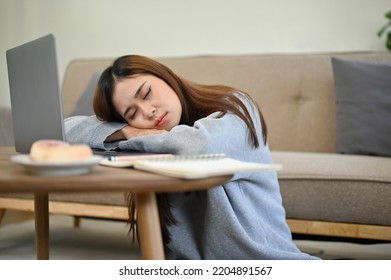 Attractive Young Asian Woman Sleeping, Leaning On A Table, Fall Asleep While Working On Her Project Assignment In The Living Room.