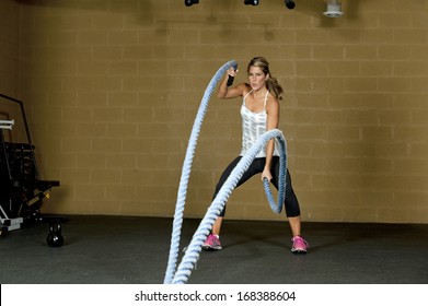 An Attractive Young And Athletic Girl Using Training Ropes In A Gym.