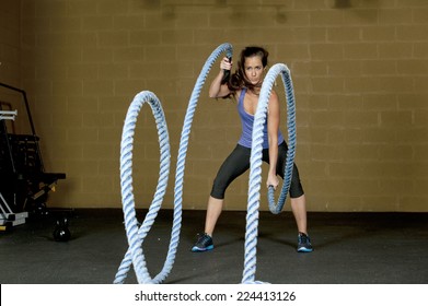 An Attractive Young And Athletic Girl Using Training Ropes In A Gym.