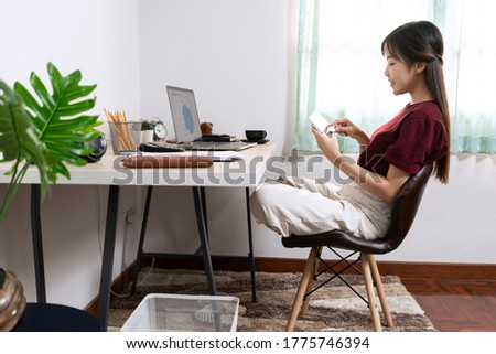 Attractive young beautiful asian woman Entrepreneur or freelancer working at home with laptop business reports and online communications on living room sofa, working remotely access concept