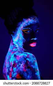 Attractive Young Black Female Model In Bright Blacklight Bodyart, Chamring Calm Female In Mindful, Peaceful, Stand Looking At Camera, Posing. Body Art, Fantastic, Fluorescent, Luminescence