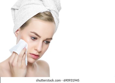 Attractive Young Blond Woman With Her Hair Wrapped In A Towel, Removing Make Up. Pretty Girl With Perfect Complexion Cleansing Her Face Using Soft Face Wipe. Isolated On White Background