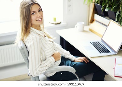 Attractive Young Blonde Office Manager Supervising And Monitoring Work Of Administrative Staff Checking Online Financial Reports Using Laptop Computer With Mock Up Screen Connected To Free Wifi