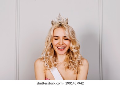 Attractive Young Blonde Woman Wearing A Diamond Golden Crown And A White Ribbon, Smiling. Beauty Contest Winner Concept.