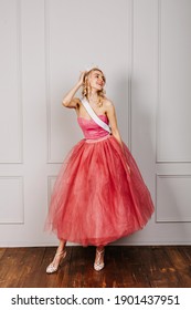 Attractive Young Blonde Woman Wearing A Crown, Pink Dress And A White Ribbon, Smiling. Beauty Contest Winner Concept.