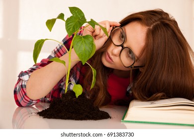 Attractive Young Botany Student With Seedling And Books