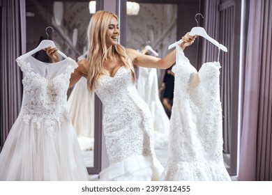 Attractive young bride is smiling while trying on wedding dress in modern wedding salon