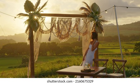 Attractive Young Bride In A Wedding White Dress. Wedding Decorations In Boho Style. Vintage String Lights Bulb Garlands Shining Above Chairs At Summer Rural Wedding.