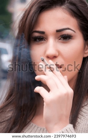 Attractive young brunette is enjoying a cigarette. Smoke addict