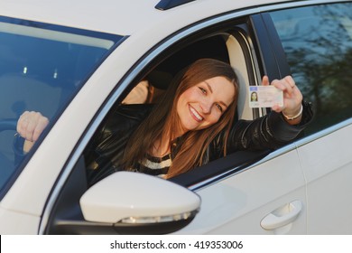 Attractive young brunette woman proudly showing her drivers license