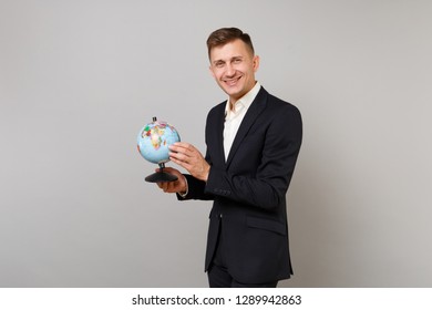 Attractive young business man in classic black suit shirt holding Earth world globe in palms isolated on grey wall background in studio. Achievement career wealth business concept. Mock up copy space