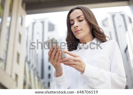 Attractive Young business woman is using the phone on a business center background.