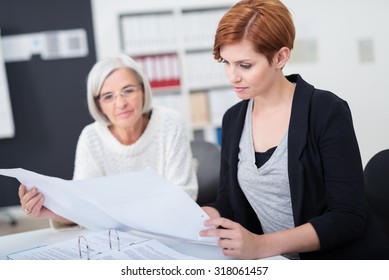 Attractive Young Businesswoman Reviewing Some Business Documents With Her Senior Colleague Inside The Office.