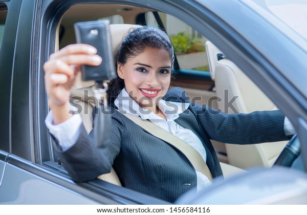 Attractive young businesswoman showing a car key\
while sitting inside the\
car