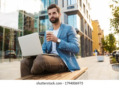 Attractive Young Bussiness Man Working On Laptop Computer While Sitting Outdoors