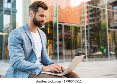 Attractive Young Bussiness Man Working On Laptop Computer While Sitting Outdoors