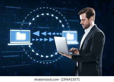 Attractive young caucasian businessman using laptop with creative digital data transfer and exchange folders on dark background. Backup data, virtual document storage or loading on cloud service - Powered by Shutterstock