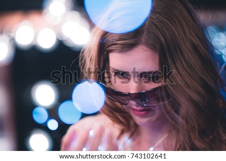 Attractive young caucasian woman poses with string lights with heavy bokeh